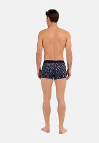 Pantaloni boxer in tessuto blu scuro con un motivo floreale colorato, dotati di una cintura a contrasto e una vestibilità aderente.