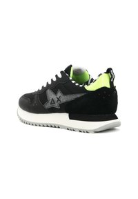 Sneaker nera con accenti in scamosciato grigio e glitter, fodera interna verde neon, suola bianca e tallone nero testurizzato. Presenta un design a zigzag.