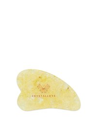 Żółte kryształowe narzędzie do masażu twarzy o gładkiej powierzchni, organicznym kształcie motyla i złotych drobinkach, z logo marki "CRYSTALLOVE".