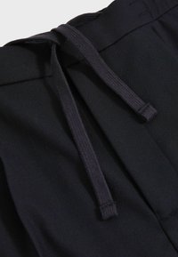 Pantaloni negri din bumbac, cu un corset elastic, textură fină și un design ajustat, cu detalii de cusătură subtile.