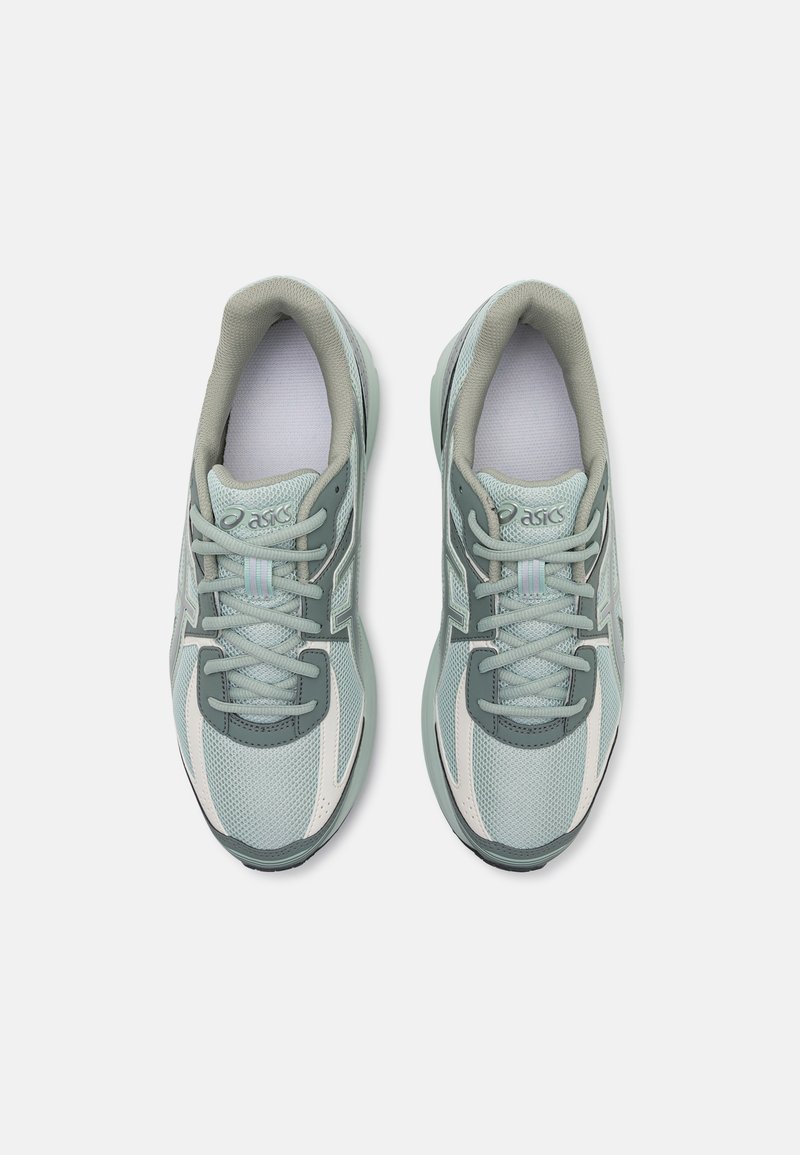 Hellgrüne und graue Sportschuhe aus Mesh-Stoff mit verstärktem Zehenbereich und Schnürverschluss. Mit einem weißen Akzent und Logo an der Seite.