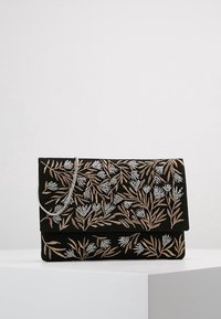 Musta clutch-laukku, jossa on kukkakirjonta hopea- ja kultalangoilla, taitettavalla läpällä ja irrotettavalla ketjuhihnalla. Sileä pinta.