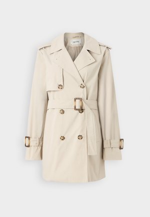 Kreminė tranšėjos palto su dvigubomis sagomis, diržu ant juosmens, pečių epauletais ir rankogalių dirželiais. Lygi audinio tekstūra.