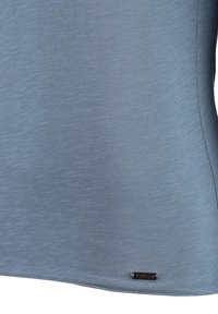 Lichtblauw shirt met korte mouwen van textuurstof, met een rechte onderrand en een klein logo-label nabij de linksonderzijde.