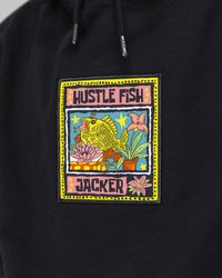 Mustapaita, jossa on värikäs brodeerattu merkki. Suunnittelussa on keltainen kala, kukkia ja teksti "HUSTLE FISH JACKER" erilaisilla väreillä.