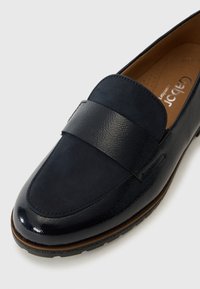 Mocassin en cuir bleu marine avec une finition lisse et brillante et une large bande texturée sur le dessus. Semelle intérieure rembourrée pour le confort.