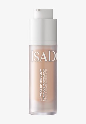 Nieprzezroczysta butelka z pompką podkładu rozświetlającego IsaDora Wake Up The Glow z SPF 50, zawierającego witaminę E i kwas hialuronowy.