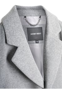 Cappotto grigio in misto lana con grandi rever, caratterizzato da un primo piano dell'etichetta "ANTONY MORATO" e un gancio a catena metallica all'interno.