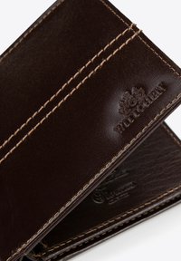 Bruine leren portemonnee met zichtbare stiksels. Heeft een gemarmerde oppervlakte, een geperst logo en meerdere kaartvakjes aan de binnenkant.