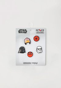 Cinco charms Jibbitz con temática de Star Wars: Darth Vader, un casco de piloto, un stormtrooper y dos íconos circulares en rojo y negro en una tarjeta de respaldo.