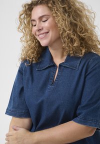 Dark denim, short-sleeve shirt with a pointed collar, placket opening, and subtle stitching details. Soft texture, casual design.