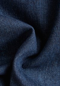 Tela de denim azul oscuro, que presenta una textura suave, con variaciones sutiles en el color y una superficie lisa.