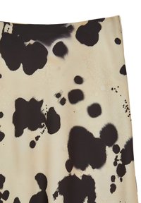 Tissu noir et beige avec un motif tacheté mélangé. Le matériau semble lisse avec des formes noires irrégulières de différentes tailles sur un fond plus clair.