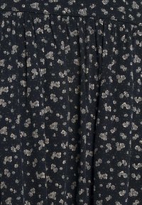 Tessuto scuro con un piccolo motivo floreale bianco e sottili punti verdi, caratterizzato da pieghe arricciate per texture e volume.