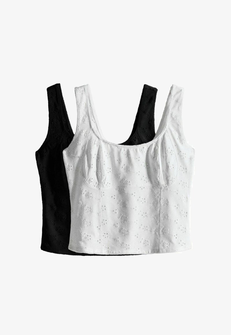 Deux crop tops sans manches avec broderie florale à œillets, un blanc devant et un noir derrière, exposés sur fond blanc.