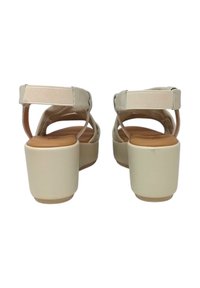 Sandali platform beige con fasce larghe e una banda elastica; texture liscia, schiena aperta e design con tacco grosso.