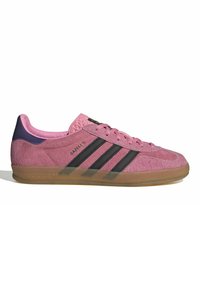 Rosa mocka Adidas Gazelle-sneaker med svarta ränder, gummisula och lila hälflik sedd från utsidan.