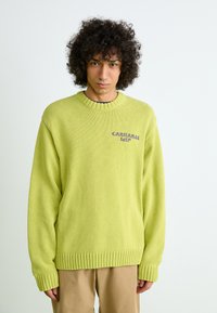 Pull en maille vert lime avec des poignets et un ourlet côtelés. Présente un col rond et le logo brodé "CARHARTT WIP" sur la poitrine.