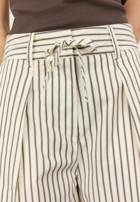 Wide-leg pants in cream with brown vertical stripes. Features a fitted waistband with a tie detail, pleats on both sides, and pockets.