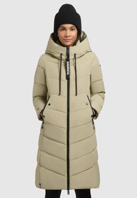 Palton puffer lung, de culoare bej deschis, cu guler înalt, închidere cu fermoar și quilt vertical. Include accente de fermoar și logo negre. Căciulă tricotată neagră.