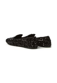 Zapatos planos negros cubiertos de lentejuelas, con una puntera redonda y una suela flexible. La textura es brillante con lentejuelas de diferentes tamaños.