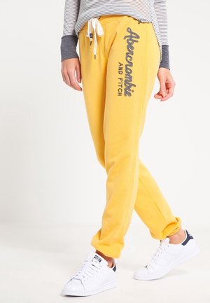 Gula mjukisbyxor med en mjuk textur, med dragsko i midjan och "Abercrombie and Fitch"-logotyp i mörk tryck på sidan.