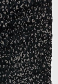 Tessuto imbottito nero con motivo a stampa animale grigia, caratterizzato da una texture arricciata e linee di cucitura orizzontali in tutta la superficie.