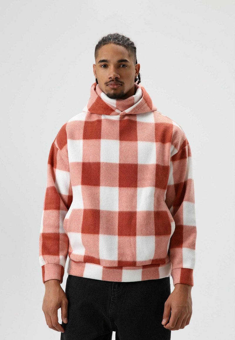 Pullover hoodie met een groot rood-wit geruit patroon, gemaakt van zachte, gestructureerde stof. Voorzien van een hoge kraag en een losse pasvorm.