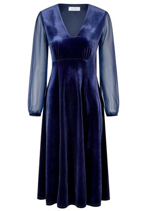 Navyblauwe fluwelen jurk met een diepe V-hals, lange doorschijnende mouwen en een vloeiende silhouet. Kenmerkt zich door een strakke taille en zachte textuur.