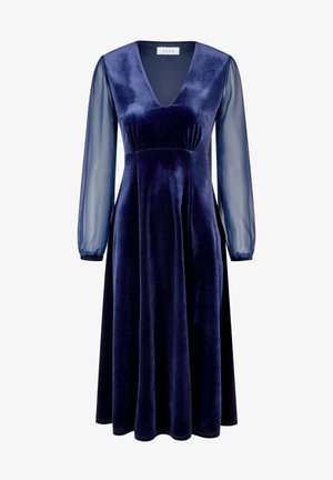 Robe en velours bleu marine avec un décolleté en V profond, des manches longues transparentes et une silhouette fluide. Elle présente une taille ajustée et une texture douce.