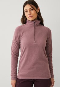 Fleece-pullover i mauve med halv-zip krave, lange ærmer og en blød tekstur. Har en rundet bund og ingen synlig branding.