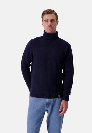 Maglione blu navy a collo alto con una texture marmorizzata, polsini e orlo a costine, indossato con jeans azzurri. Vestibilità rilassata per il massimo comfort.