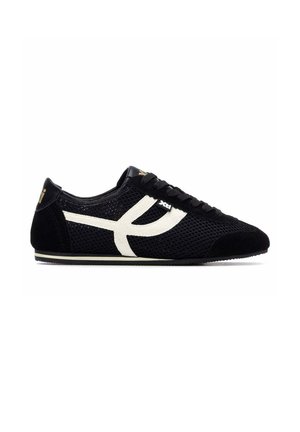 Zapatilla deportiva de malla negra con una franja curva blanca en el lateral, cordones negros y una suela baja y plana vista desde el lado izquierdo.