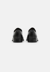 Schwarze Lederdressschuhe mit glatter Oberfläche, runder Zehenform, niedrigem Absatz und minimalen Nähten auf dem Obermaterial.