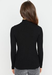 Schwarzer, gerippter Pullover mit Stehkragen und langen Ärmeln. Hat eine taillierte Silhouette und einen asymmetrischen Saum, aus weichem Strickmaterial gefertigt.