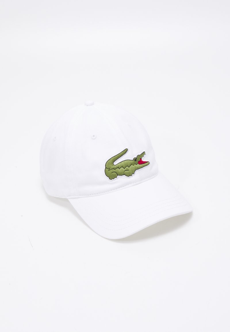 Gorra de béisbol blanca hecha de algodón que presenta un logo de cocodrilo verde bordado en la parte frontal. La gorra tiene un visera curvada y agujeros de ventilación.