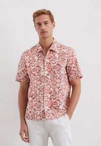 Korte mouwen shirt van lichtgewicht stof met een bloemmotief in rood op een lichtbeige achtergrond; knoopsluiting aan de voorkant en kraag.