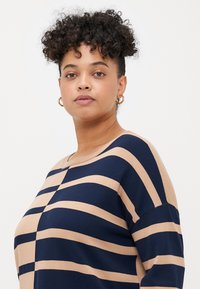 Navy and beige striped sweater with a round neckline and short sleeves, featuring a soft, smooth texture and a loose fit.
