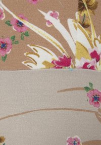 Beżowy i brązowy materiał w kwiaty z różowymi kwiatami i zielonymi liśćmi, ozdobiony skomplikowanymi złotymi i białymi wzorami liści.