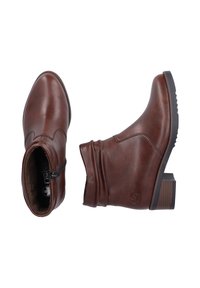 Bottines en cuir marron avec un design décontracté, fermeture éclair latérale et semelle texturée. Présentent un talon empilé et des détails de surpiqûres subtils.