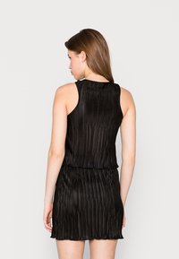 Vestido preto plissado com um design sem mangas, apresentando um decote redondo e uma cintura elástica. Textura suave com uma silhueta fluida.