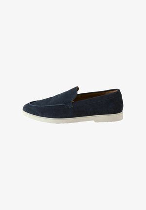 Mocassin slip-on en daim bleu marine avec semelle en caoutchouc blanche, bout moc arrondi et petit talon, présenté sur fond blanc.