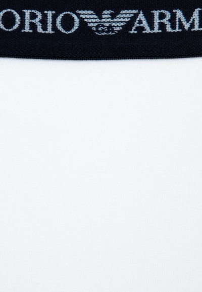 Tecido branco com um acabamento texturizado, apresentando uma faixa elástica azul-marinho na parte superior em relevo com o logotipo "Emporio Armani" em azul claro.