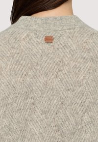 Hellgrauer Strickpullover mit einem Diamantmuster und geripptem Rundhalsausschnitt, mit einem kleinen Lederetikett mit der Aufschrift "Trussardi" auf der Rückseite.