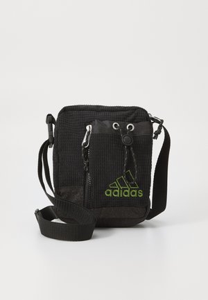 Svart texturerad crossbody-väska med justerbar rem, framficka med dragkedja och grön Adidas-logotyp. Tillverkad av slitstarkt material med en kompakt design.