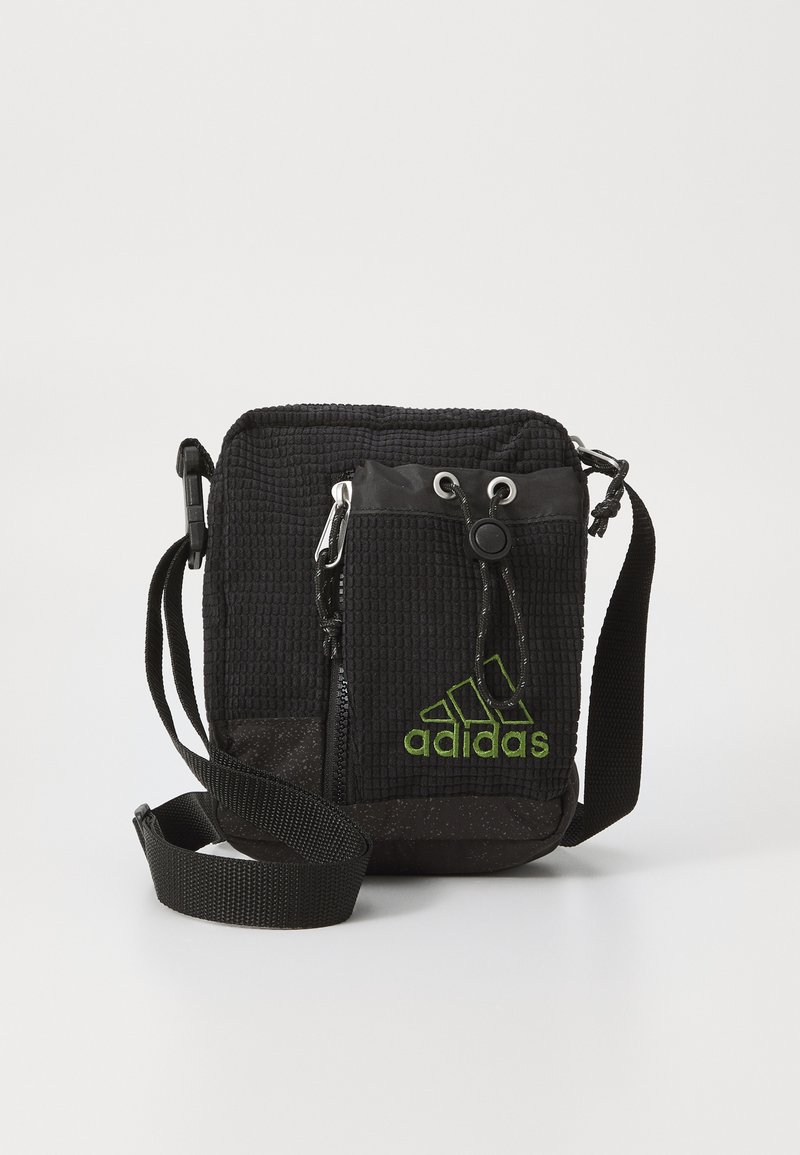 Borsa a tracolla nera con texture, dotata di tracolla regolabile, tasca con zip frontale e logo verde Adidas. Realizzata in materiale resistente con un design compatto.