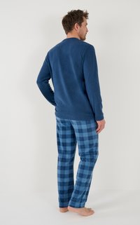 Blauwe lange mouwen top gemaakt van zachte stof, gecombineerd met blauwe geruite flanellen pants met afwisselend lichte en donkere vierkanten.