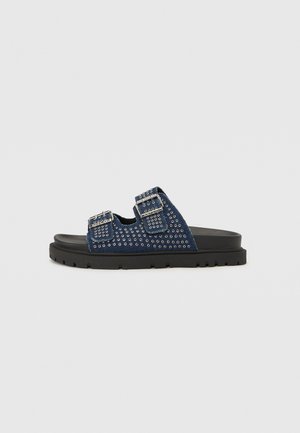 Blaue Rutschsandalen mit Nietenverzierung, verstellbaren Riemen, einem strukturierten Stoff-Obermaterial und einer klobigen schwarzen Gummisohle.