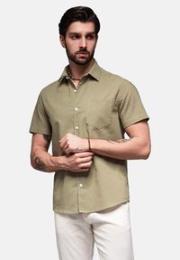 Lichtgekleurde khaki shirt met korte mouwen in een katoenmix, voorzien van een button-down kraag, voorzak en een gestructureerde pasvorm. Draag het met een witte broek.