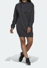 Grå sweatshirtklänning med hög krage och kvartslång dragkedja. Har elastisk nederkant och ärmar, tillverkad av mjukt tyg, lämplig för avslappnad användning.